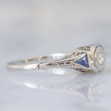 Solitario Art Déco in oro bianco 18K con diamante di taglio brillante (0.08ct ca.) e zaffiri di taglio triangolare, anni ‘30