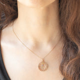 Ciondolo antico in oro giallo 9K con decorazioni naturalistiche e con rodine decorato da perline bianche e da ametista, anni ‘10/‘20