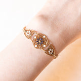 Braccialetto semirigido in oro giallo 14K con decorazioni floreali con smalti bianchi, rossi, verdi e blu e con lavorazioni a traforo, anni ‘50/‘60