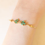 Braccialetto semirigido in oro giallo 14K con smeraldi (0.50ctw ca.) e diamanti (0.02ctw ca.), anni ‘70/‘80