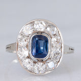 Anello a margherita antico in oro bianco con zaffiro (0.70ct ca.) e diamanti di taglio vecchia miniera (1ctw ca.), anni ‘20/‘30