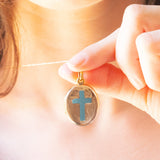 Ciondolo portafoto vittoriano di forma ovale con lamina in oro giallo 9K su metallo e con croce decorata da smalti azzurri, primi del ‘900