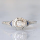 Solitario Art Déco in oro bianco 18K con diamante di taglio brillante (0.08ct ca.) e zaffiri di taglio triangolare, anni ‘30