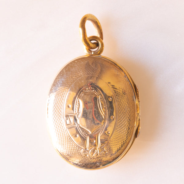 Ciondolo portafoto vittoriano di forma ovale con lamina in oro giallo 9K su metallo e con croce decorata da smalti azzurri, primi del ‘900