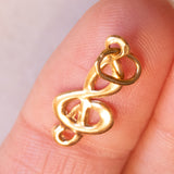 Lotto comprendente ciondolo in oro 18K con ametista, ciondolo in oro 18K con zaffiro e ciondolo a forma di chiave di violino in oro 18K