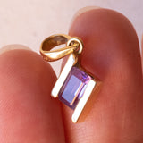 Lotto comprendente ciondolo in oro 18K con ametista, ciondolo in oro 18K con zaffiro e ciondolo a forma di chiave di violino in oro 18K