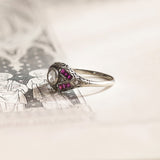 Anello di transizione Art Nouveau-Art Déco in oro bianco 18K con diamante centrale (0.43ct ca.) e rubini, anni ‘20/‘30