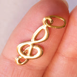 Lotto comprendente ciondolo in oro 18K con ametista, ciondolo in oro 18K con zaffiro e ciondolo a forma di chiave di violino in oro 18K