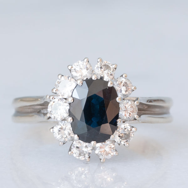 Anello a margherita vintage in oro bianco 18K con zaffiro (1ct ca.) e diamanti di taglio brillante (0.60ctw ca.), anni ‘70