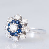 Anello a fiore vintage in oro bianco 14K con diamanti di taglio brillante (0.84ctw ca.) e zaffiri (0.32ctw ca.), anni ‘70