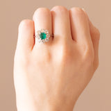 Anello a margherita vintage in oro bianco 18K con smeraldo (0.65ct ca.) e diamanti di taglio brillante (1.28ctw ca.), anni ‘60/‘70