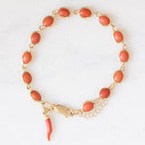 Pulseira vintage em ouro amarelo 18K com coral laranja e fecho decorado com um pingente de chifre da sorte, década de 70