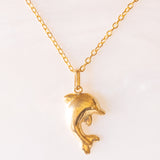 Collana con catenina in argento dorato e con tre ciondoli a forma di delfino in oro giallo 18K, di ancora in oro giallo 18K e di tartaruga in oro giallo 14K