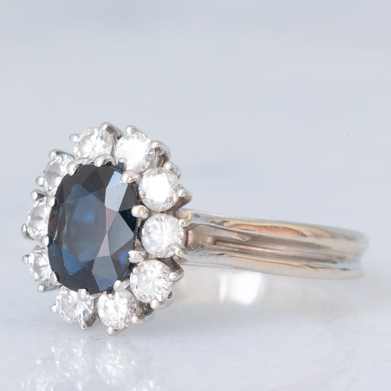 Anello a margherita vintage in oro bianco 18K con zaffiro (1ct ca.) e diamanti di taglio brillante (0.60ctw ca.), anni ‘70