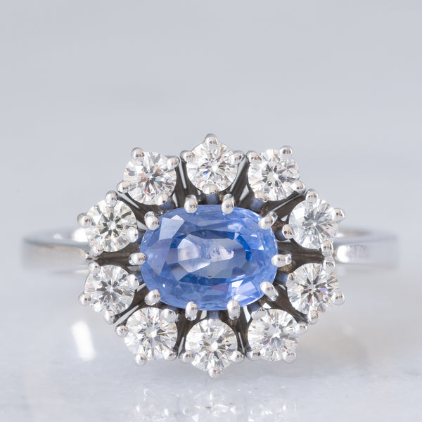 Anello a margherita in oro bianco 18K con zaffiro azzurro (0.80ct ca.) e diamanti di taglio brillante (0.70ctw ca.), anni ‘70/‘80