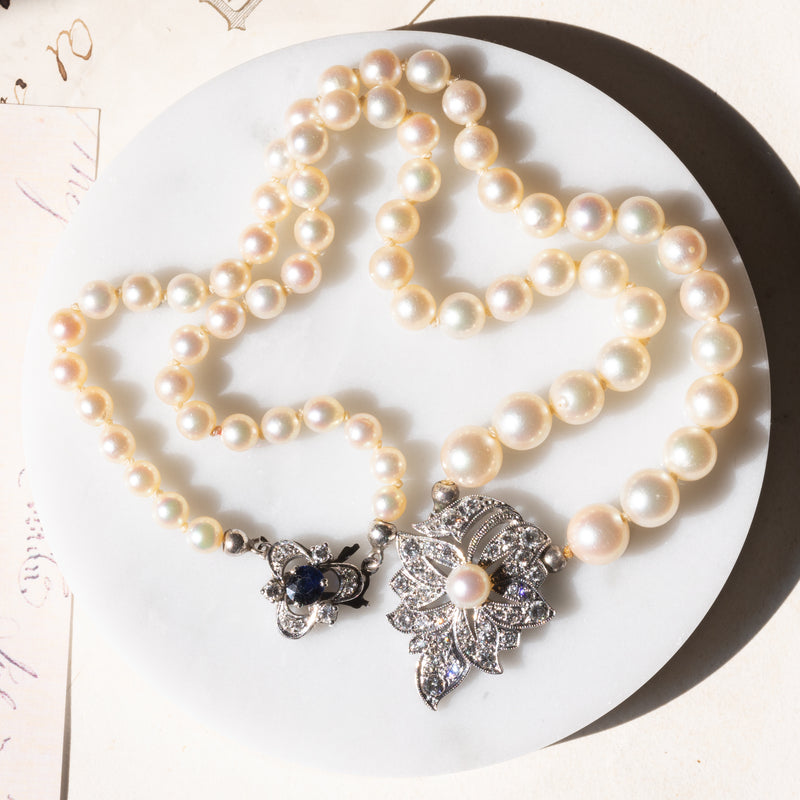 Collana vintage con filo di perle bianche e con decorazioni in oro bianco 18K e 14K con diamanti (1.20ctw ca.) e zaffiro (0.40ct ca.), anni ‘60