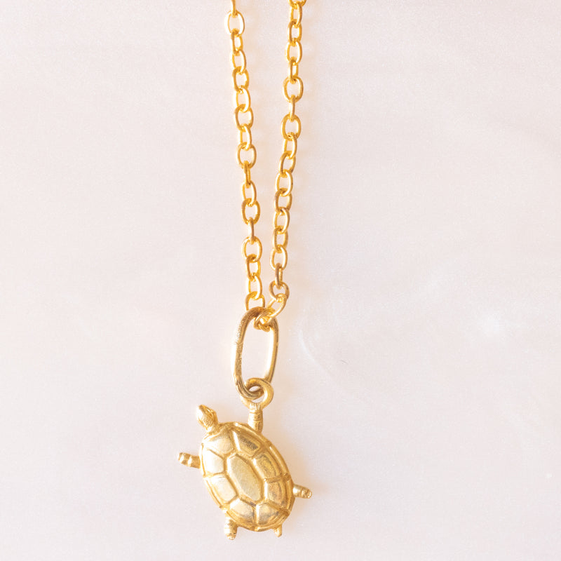 Collana con catenina in argento dorato e con tre ciondoli a forma di delfino in oro giallo 18K, di ancora in oro giallo 18K e di tartaruga in oro giallo 14K