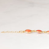 Pulseira vintage em ouro amarelo 18K com coral laranja e fecho decorado com um pingente de chifre da sorte, década de 70