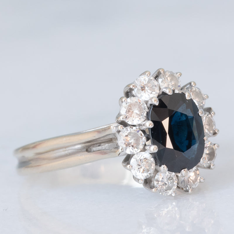 Anello a margherita vintage in oro bianco 18K con zaffiro (1ct ca.) e diamanti di taglio brillante (0.60ctw ca.), anni ‘70