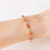 Pulseira vintage em ouro amarelo 18K com coral laranja e fecho decorado com um pingente de chifre da sorte, década de 70