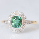 Anello a margherita antico in oro giallo 18K con tormalina verde (1ct ca.) e diamanti di taglio vecchia miniera (0.50ctw ca.), anni ‘20/‘30