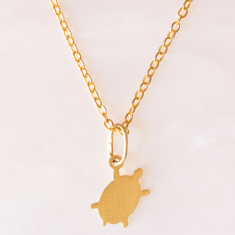 Collana con catenina in argento dorato e con tre ciondoli a forma di delfino in oro giallo 18K, di ancora in oro giallo 18K e di tartaruga in oro giallo 14K