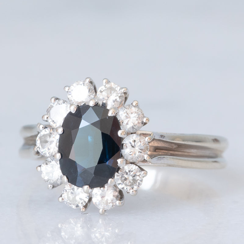 Anello a margherita vintage in oro bianco 18K con zaffiro (1ct ca.) e diamanti di taglio brillante (0.60ctw ca.), anni ‘70