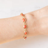 Pulseira vintage em ouro amarelo 18K com coral laranja e fecho decorado com um pingente de chifre da sorte, década de 70