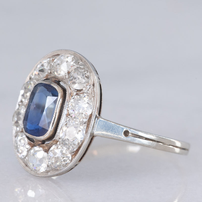 Anello a margherita antico in oro bianco con zaffiro (0.70ct ca.) e diamanti di taglio vecchia miniera (1ctw ca.), anni ‘20/‘30