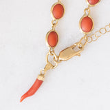 Pulseira vintage em ouro amarelo 18K com coral laranja e fecho decorado com um pingente de chifre da sorte, década de 70