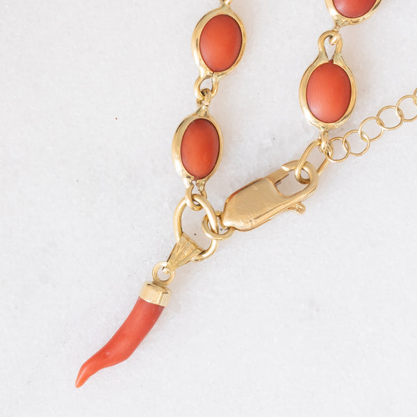 Braccialetto vintage in oro giallo 18K con corallo arancione e con chiusura decorata da charm cornetto portafortuna, anni ‘70