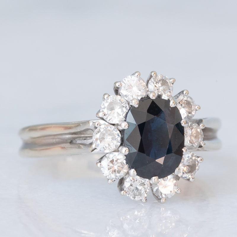 Anello a margherita vintage in oro bianco 18K con zaffiro (1ct ca.) e diamanti di taglio brillante (0.60ctw ca.), anni ‘70