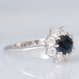 Anello a margherita vintage in oro bianco 18K con zaffiro (1.20ct ca.) e diamanti di taglio brillante (0.80ctw ca.), anni ‘70