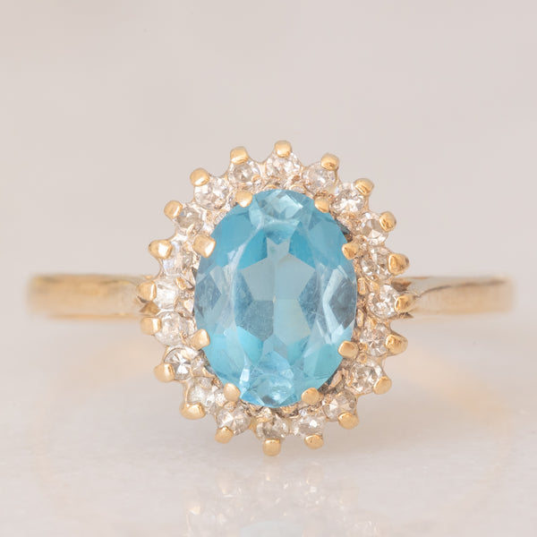 Anello a margherita vintage in oro giallo 9K con topazio azzurro (1.50ct ca.) e diamanti (0.10ctw ca.), anno 1988
