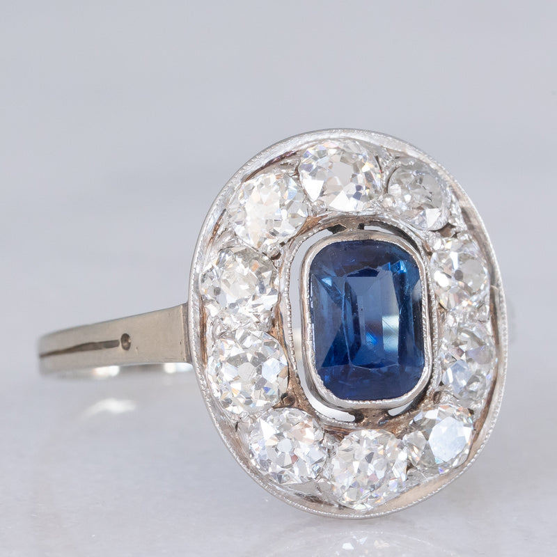 Anello a margherita antico in oro bianco con zaffiro (0.70ct ca.) e diamanti di taglio vecchia miniera (1ctw ca.), anni ‘20/‘30