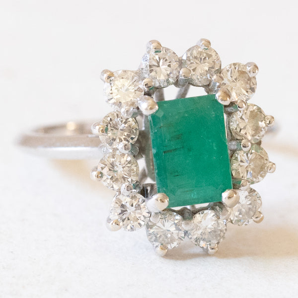 Anello vintage a margherita in oro bianco 18K con smeraldo (0.90ct ca.) e diamanti di taglio brillante (1.20ctw ca.), anni ‘60
