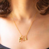 Collana con catenina in argento dorato e con tre ciondoli a forma di delfino in oro giallo 18K, di ancora in oro giallo 18K e di tartaruga in oro giallo 14K