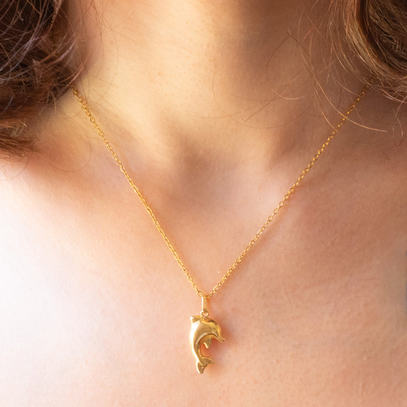 Collana con catenina in argento dorato e con tre ciondoli a forma di delfino in oro giallo 18K, di ancora in oro giallo 18K e di tartaruga in oro giallo 14K