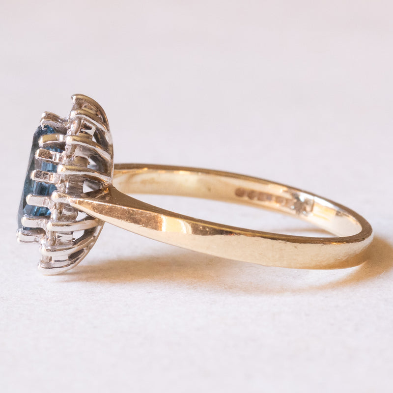 Anello a margherita moderno in oro giallo e in oro bianco 9K con topazio azzurro (1.30ct ca.) e diamanti di taglio brillante (0.16ctw ca.), anni ‘70/‘80
