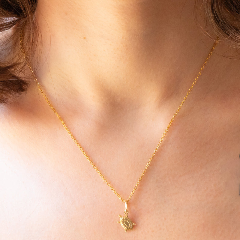 Collana con catenina in argento dorato e con tre ciondoli a forma di delfino in oro giallo 18K, di ancora in oro giallo 18K e di tartaruga in oro giallo 14K