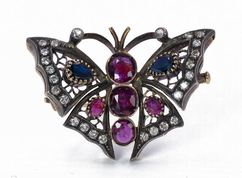 Spilla vintage a farfalla in oro 18k e argento con diamanti, zaffiri e rubini. Anni 50