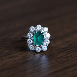 Vintage Gänseblümchenring aus 18 Karat Weißgold mit Smaragd (ca. 0.70 ct) und Diamanten im Brillantschliff (ca. 1.3 ct), 50er / 60er Jahre